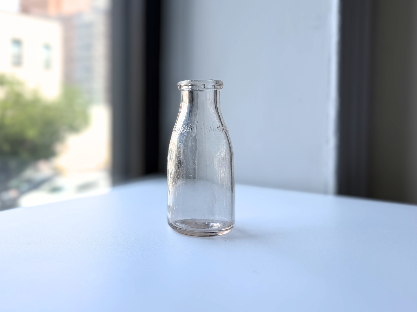 Front view of a vintage clear glass Milk for Health milk bottle