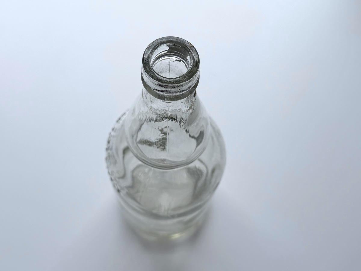 Top-down view of a James Martin whiskey bottle's open mouth with a remnant of the original cap label still attached.