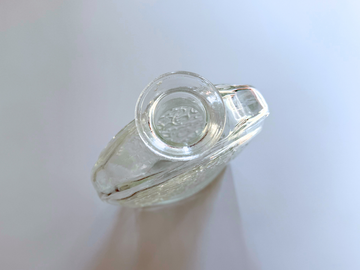 Schenley decanter base held in hand showing the oval silhouette and scrollwork detail.