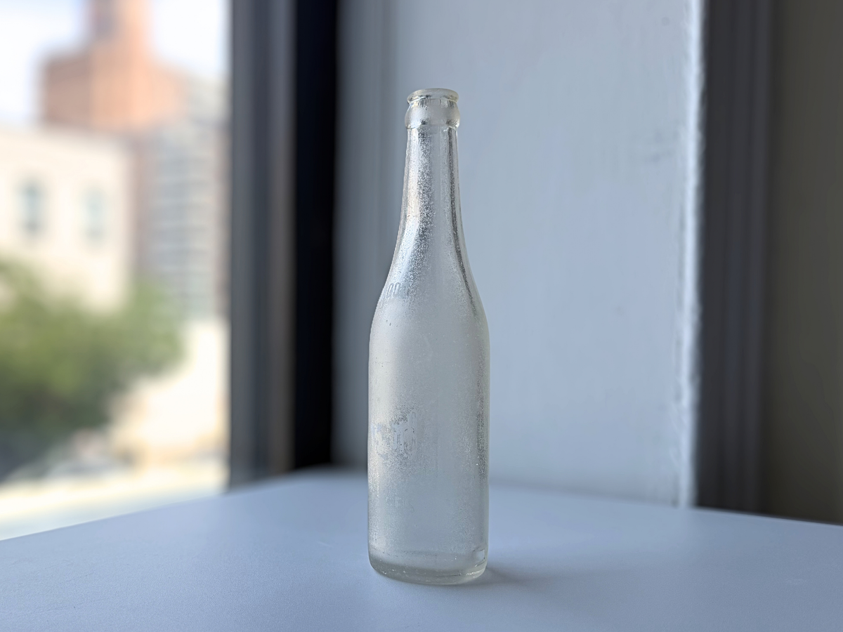 Front view of a vintage Hollywood soda bottle with a frosted ocean patina and faint lettering