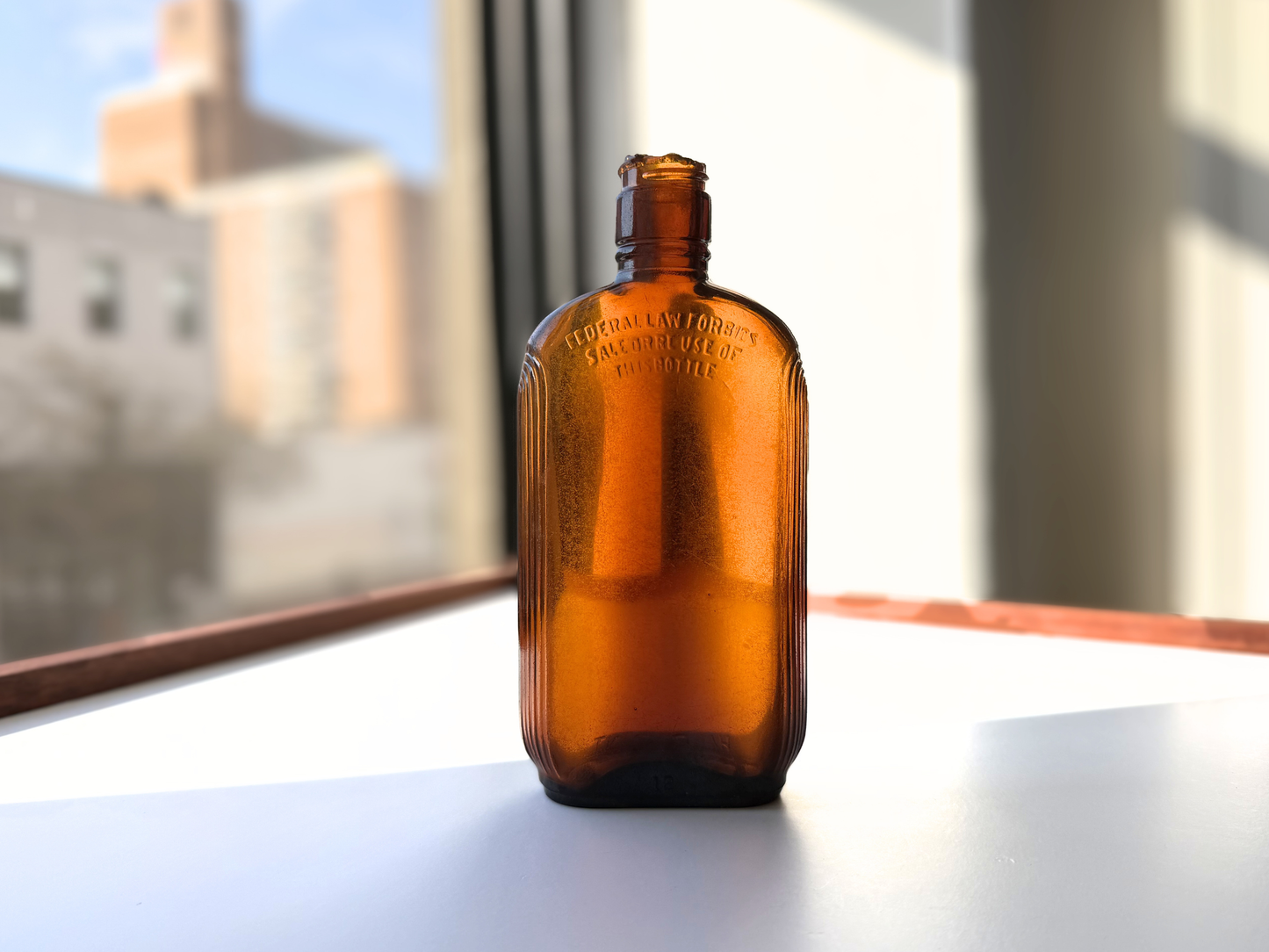 Sea-worn amber glass Art Deco flask displayed on a windowsill with soft natural light