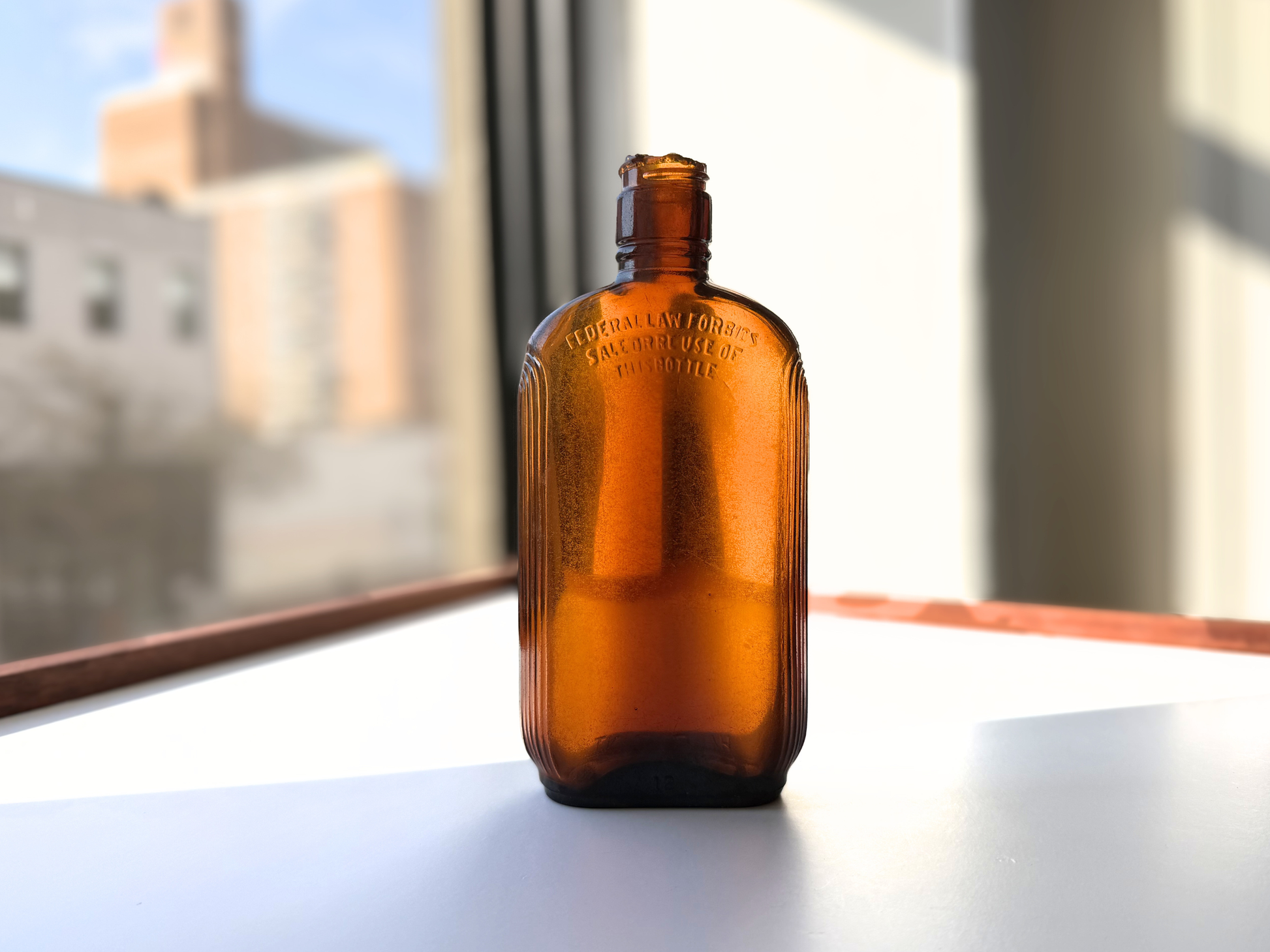 Sea-worn amber glass Art Deco flask displayed on a windowsill with soft natural light