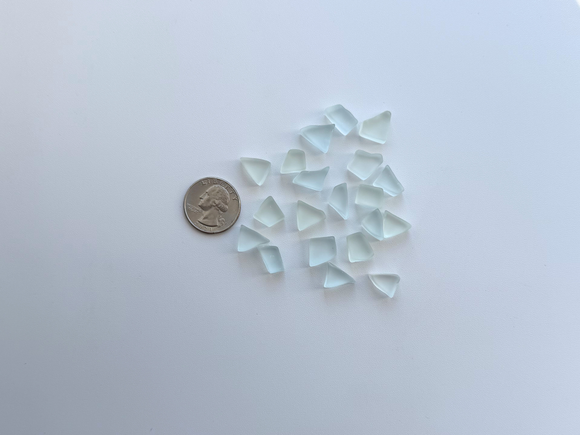 Tumbled sea glass pieces next to a coin for size scale, showing 10 to 15mm width
