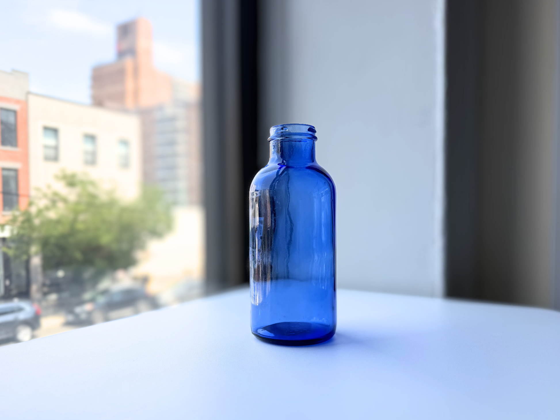 Vintage cobalt blue glass pharmaceutical bottle in natural window light