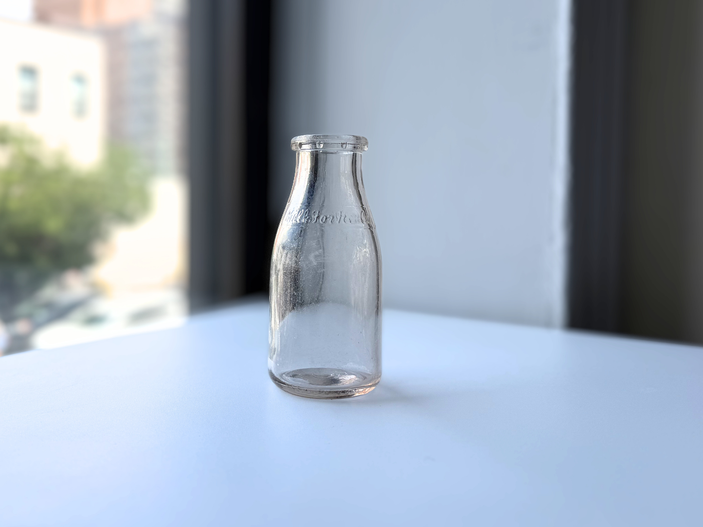 Vintage clear glass Milk for Health milk bottle near a window with natural light