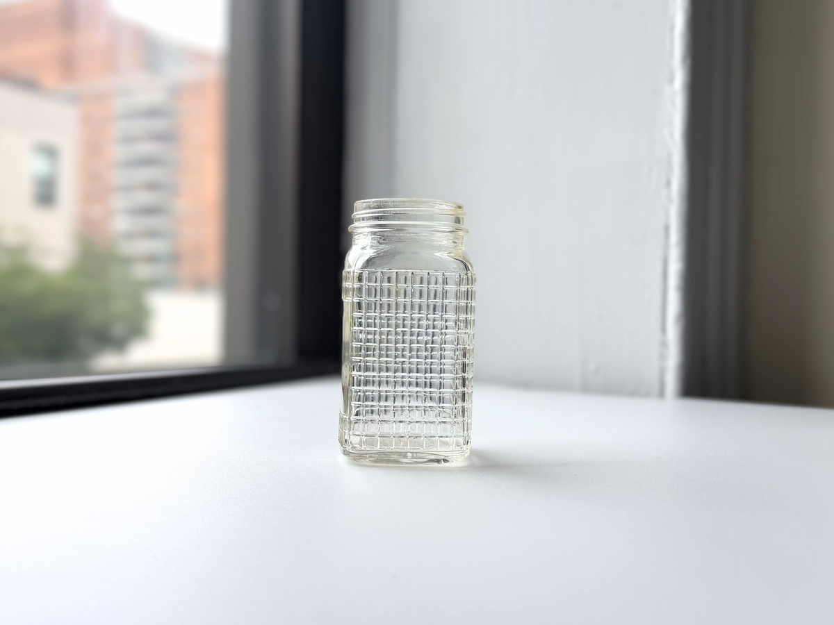 Ball waffle glass jar on a windowsill at an angle.