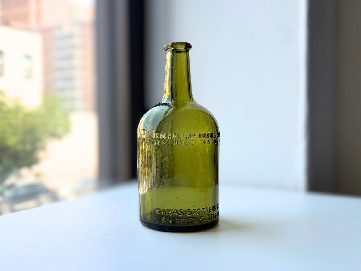 Front of the vintage green glass bottle with embossed Chivas Brothers Ltd Aberdeen Scotland lettering near the base