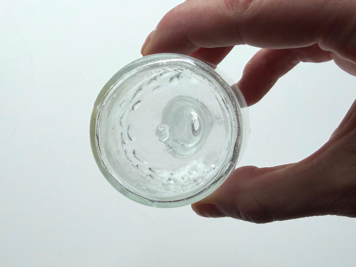 Hobnail glass bud vase base held in hand showing the raised dot texture.