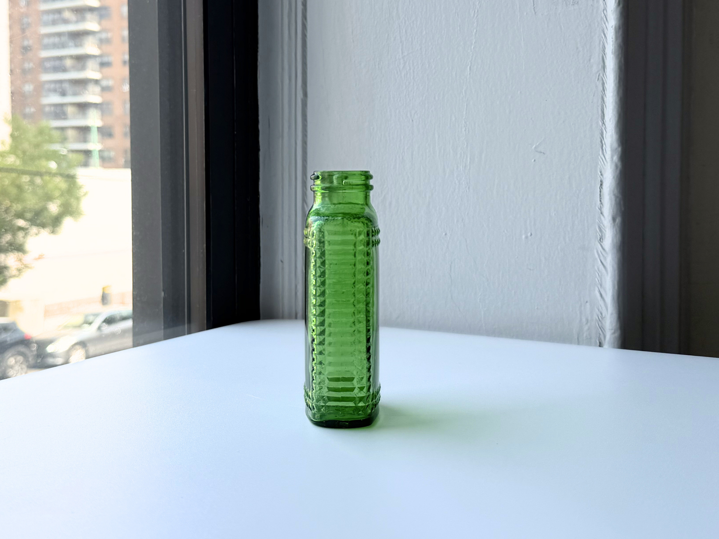 Base of a vintage kelly green Airwick hobnail glass bottle showing embossed mold number and maker's mark