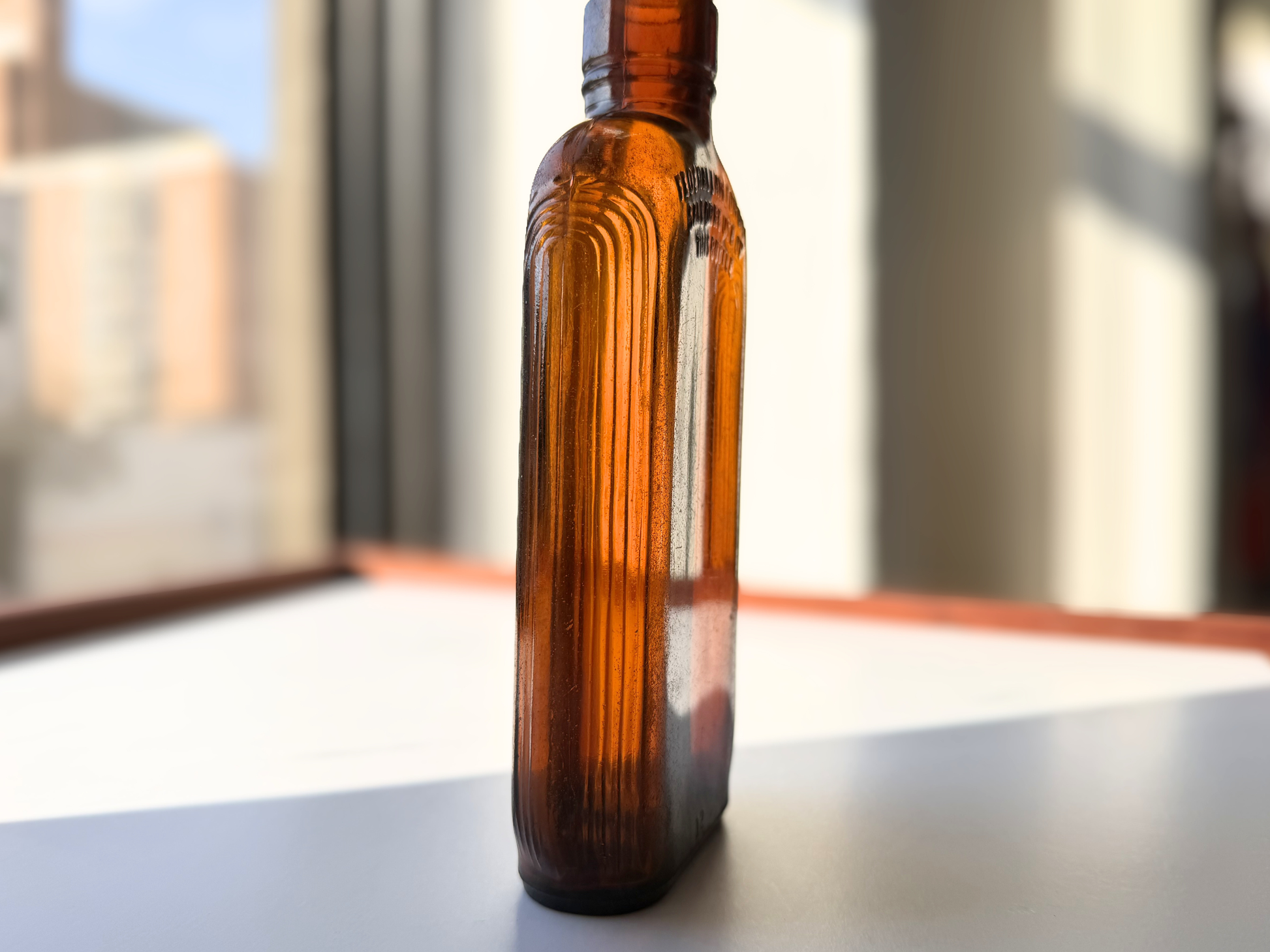 Side view of a sea-worn amber glass flask showing its ribbed edge detail