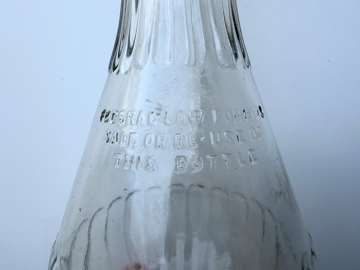 Embossed Federal Law reuse warning on the lower body of a vintage ribbed clear glass genie bottle