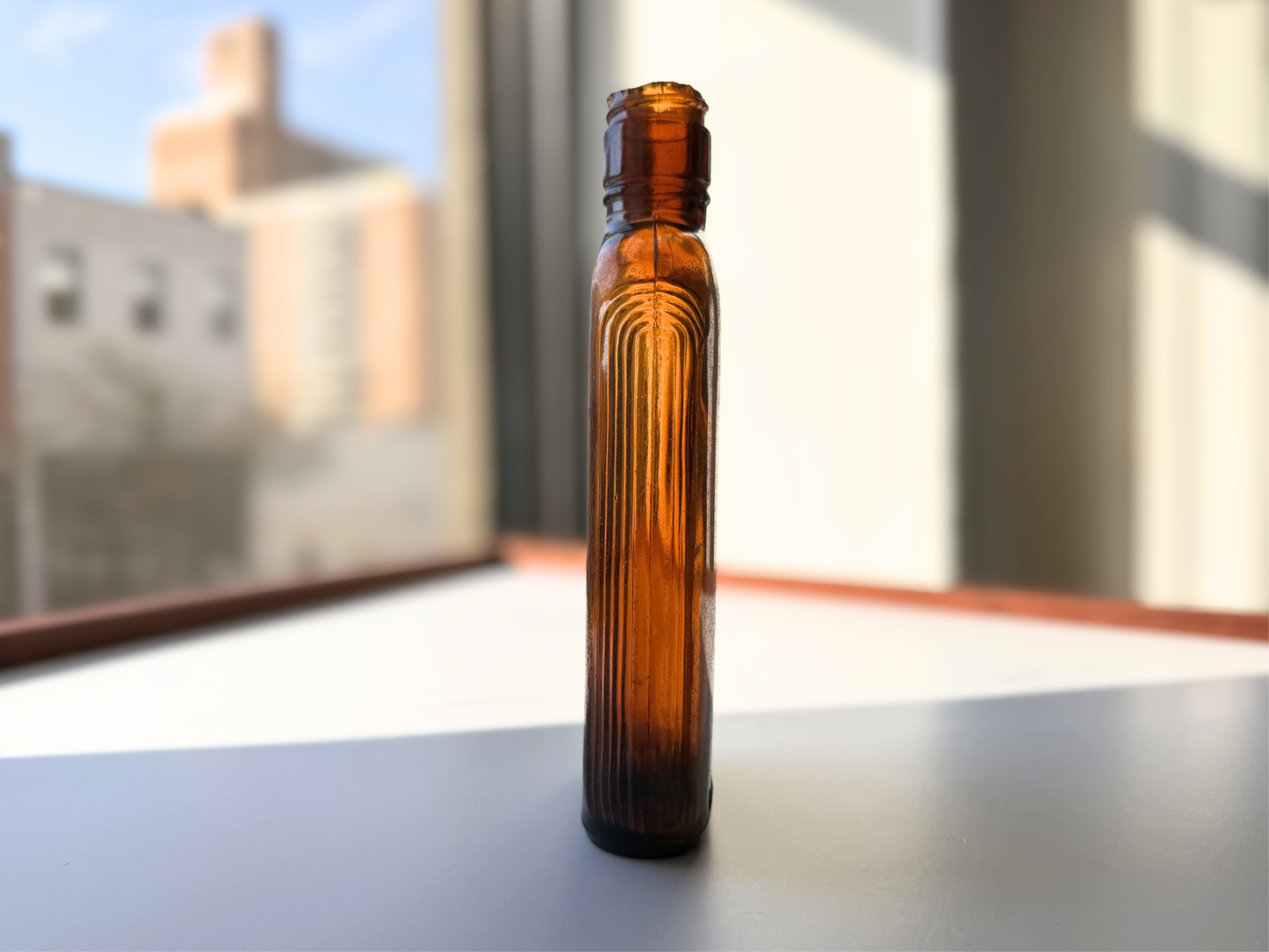 Close side view of a sea-worn amber glass Art Deco flask highlighting the ribbed texture