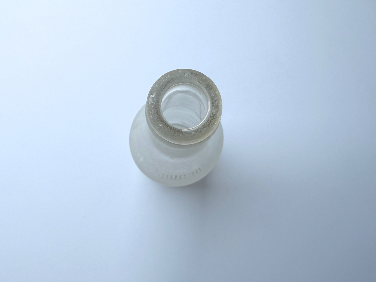 Top-down view into the open mouth of a sea-worn frosted clear glass soda bottle