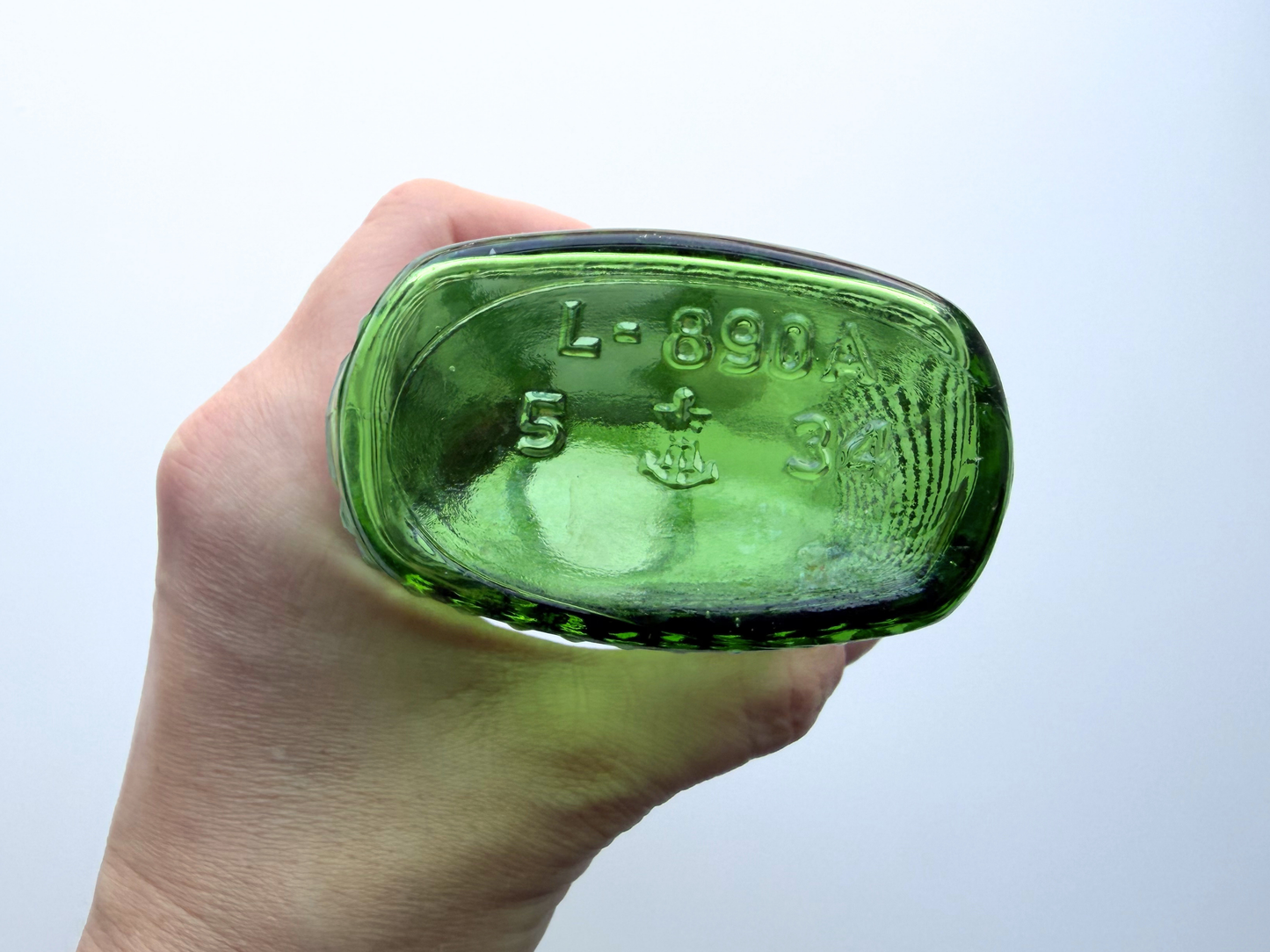 Overhead view looking down into the mouth of a vintage kelly green Airwick hobnail glass bottle