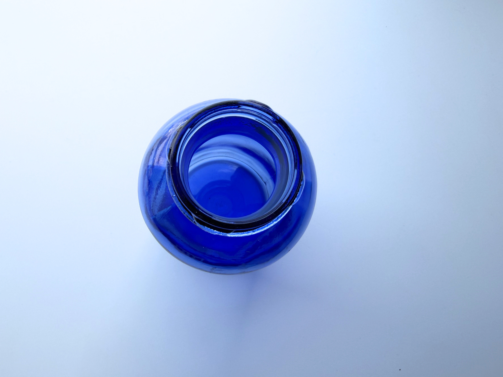 Overhead view looking down into the opening of a vintage cobalt blue glass pharmaceutical bottle