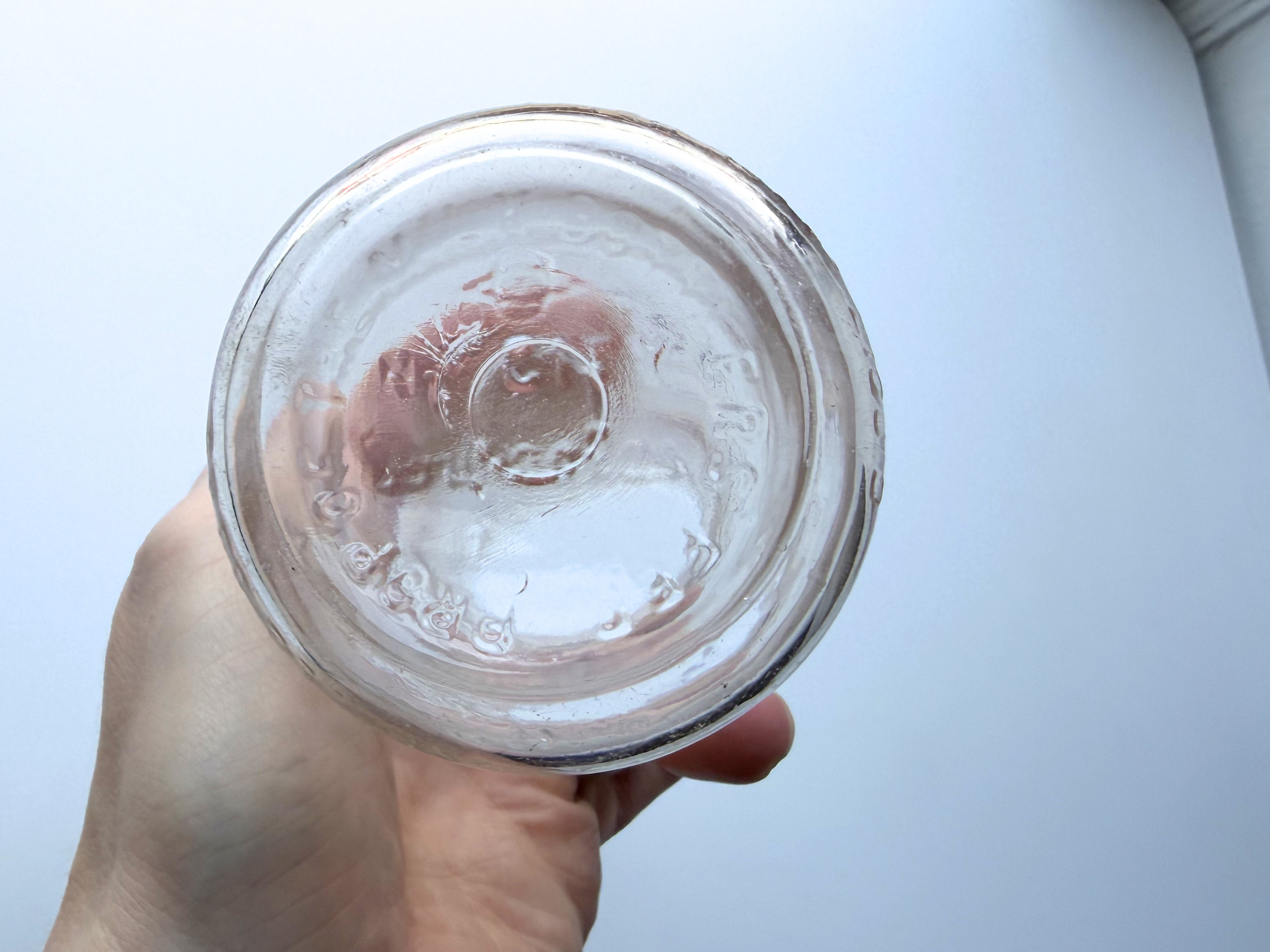 Hand holding a vintage Milk for Health glass milk bottle, viewed from above into the opening