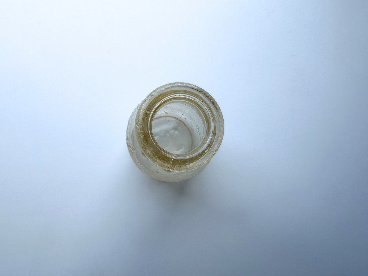 Top-down view into the mouth of a sea-worn Elmhurst Cream Co glass dairy bottle