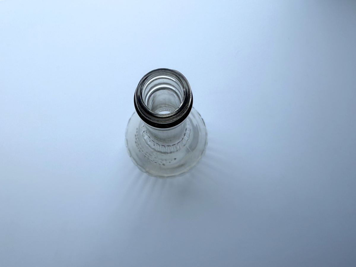 Top-down view into the open mouth of a vintage clear glass genie bottle