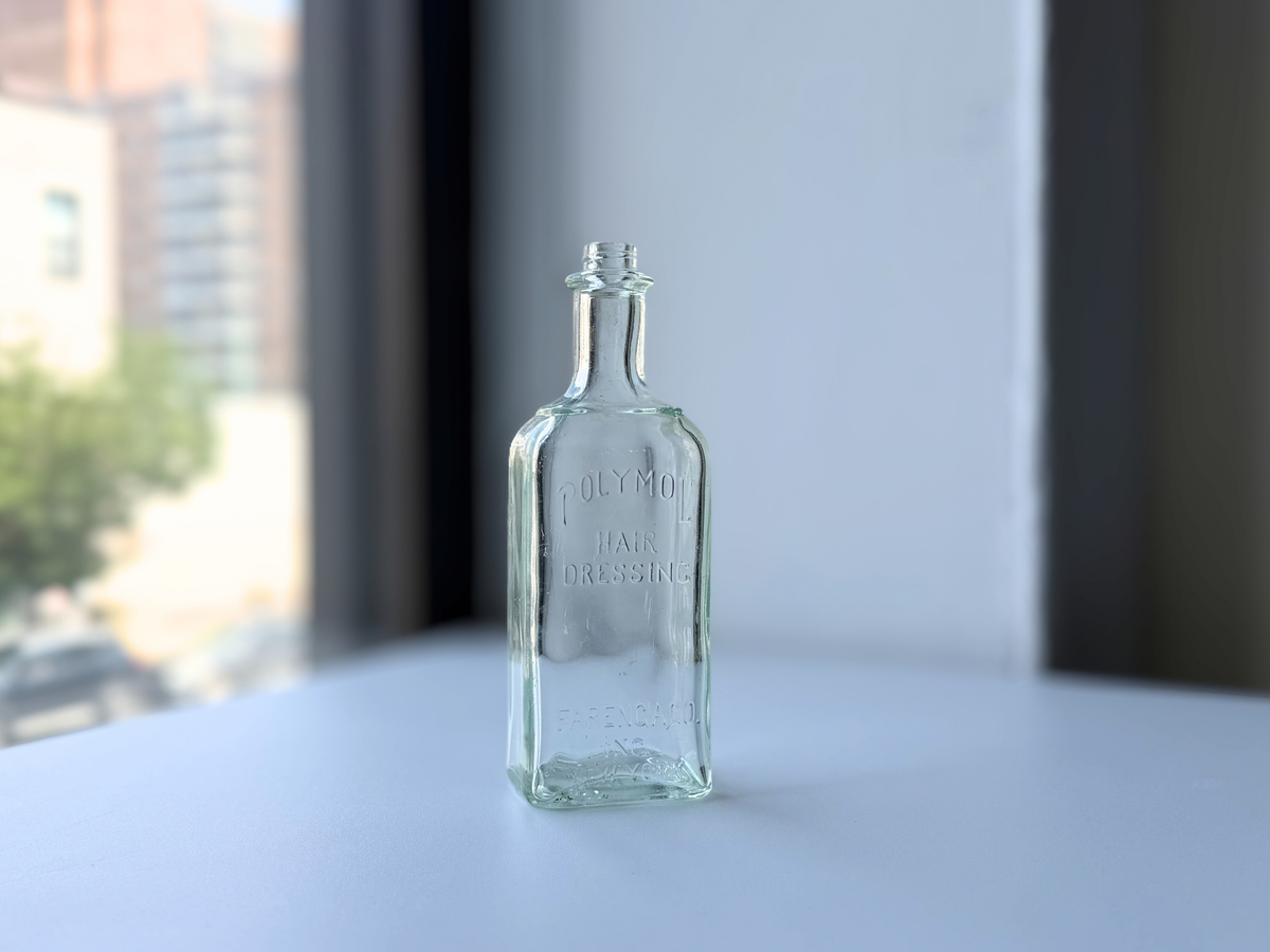 Front label detail of the vintage Polymol bottle in soft window light