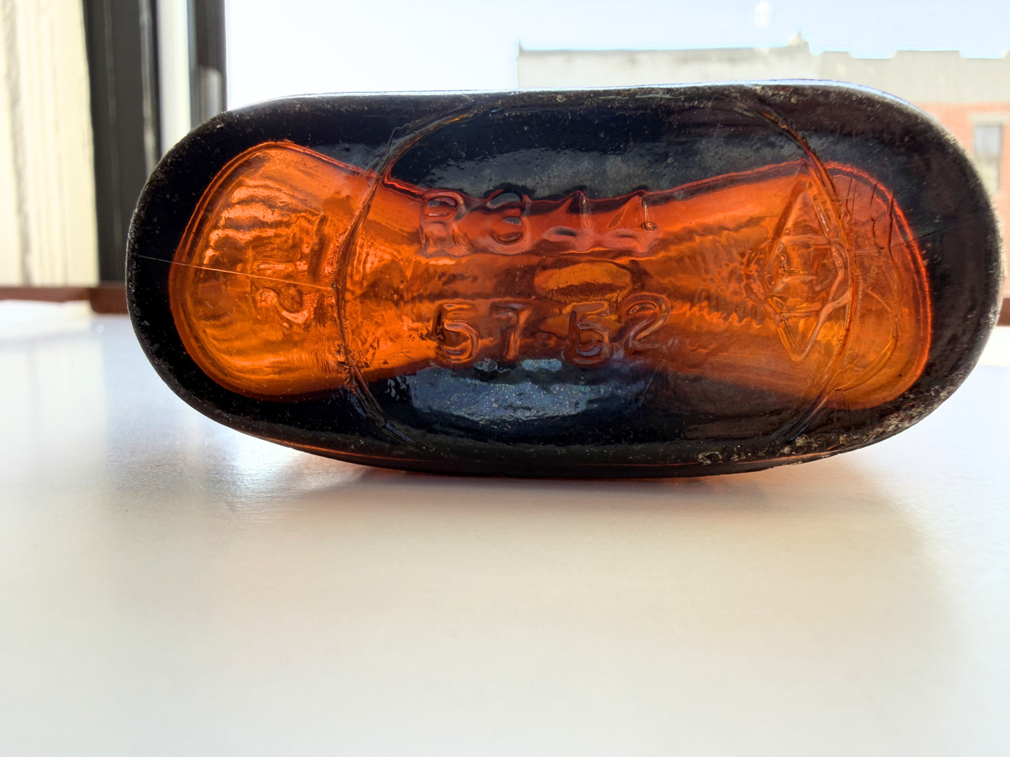 Overhead view of a sea-worn amber glass flask showing its flattened oval Art Deco shape