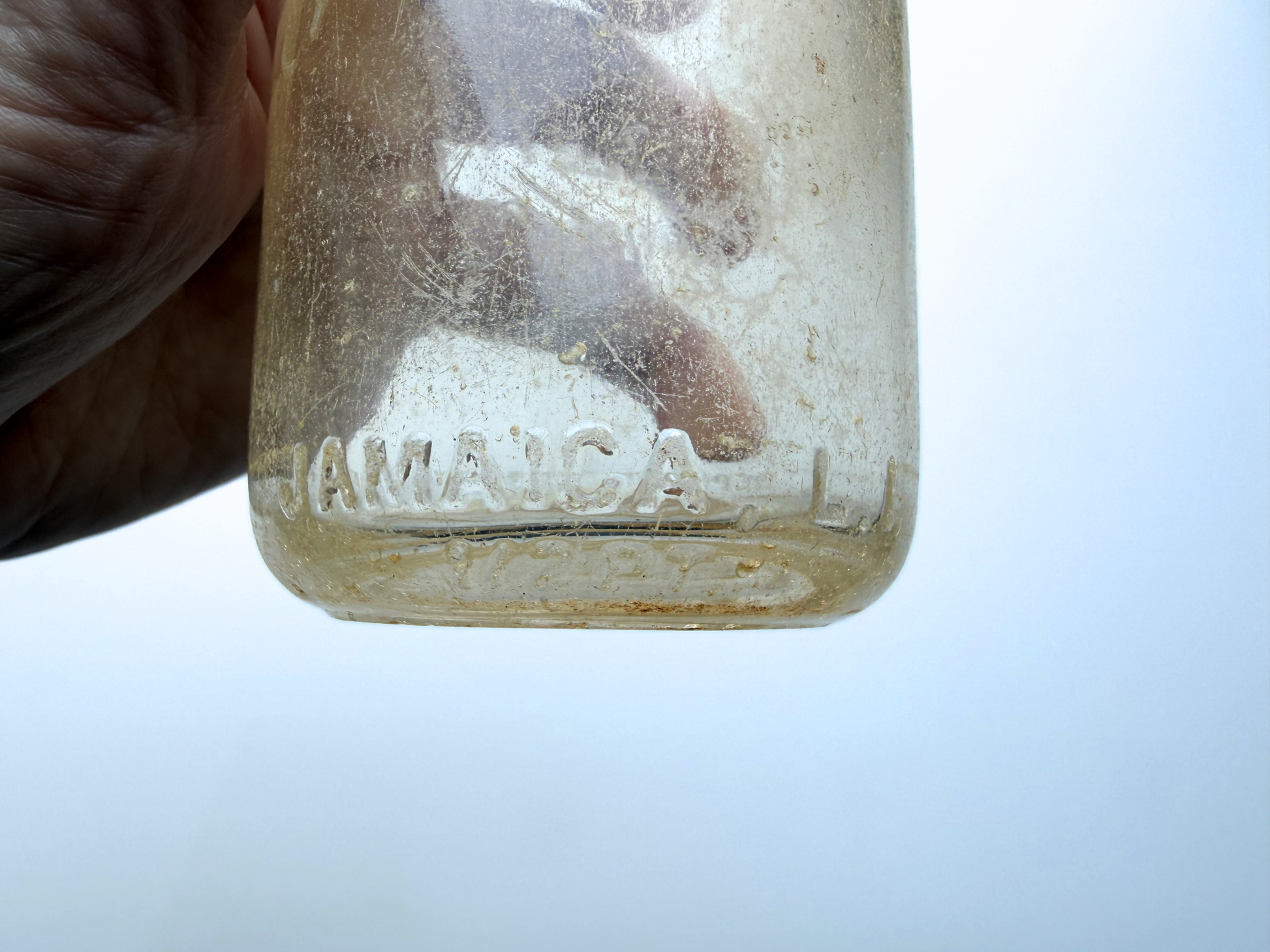 Close-up of side embossed lettering on a sea-worn Elmhurst Cream Co dairy bottle