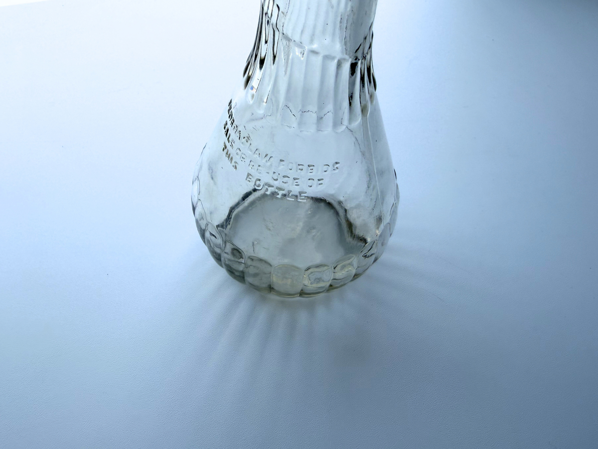 Close view of the ribbed lower body and base of a vintage clear glass genie bottle
