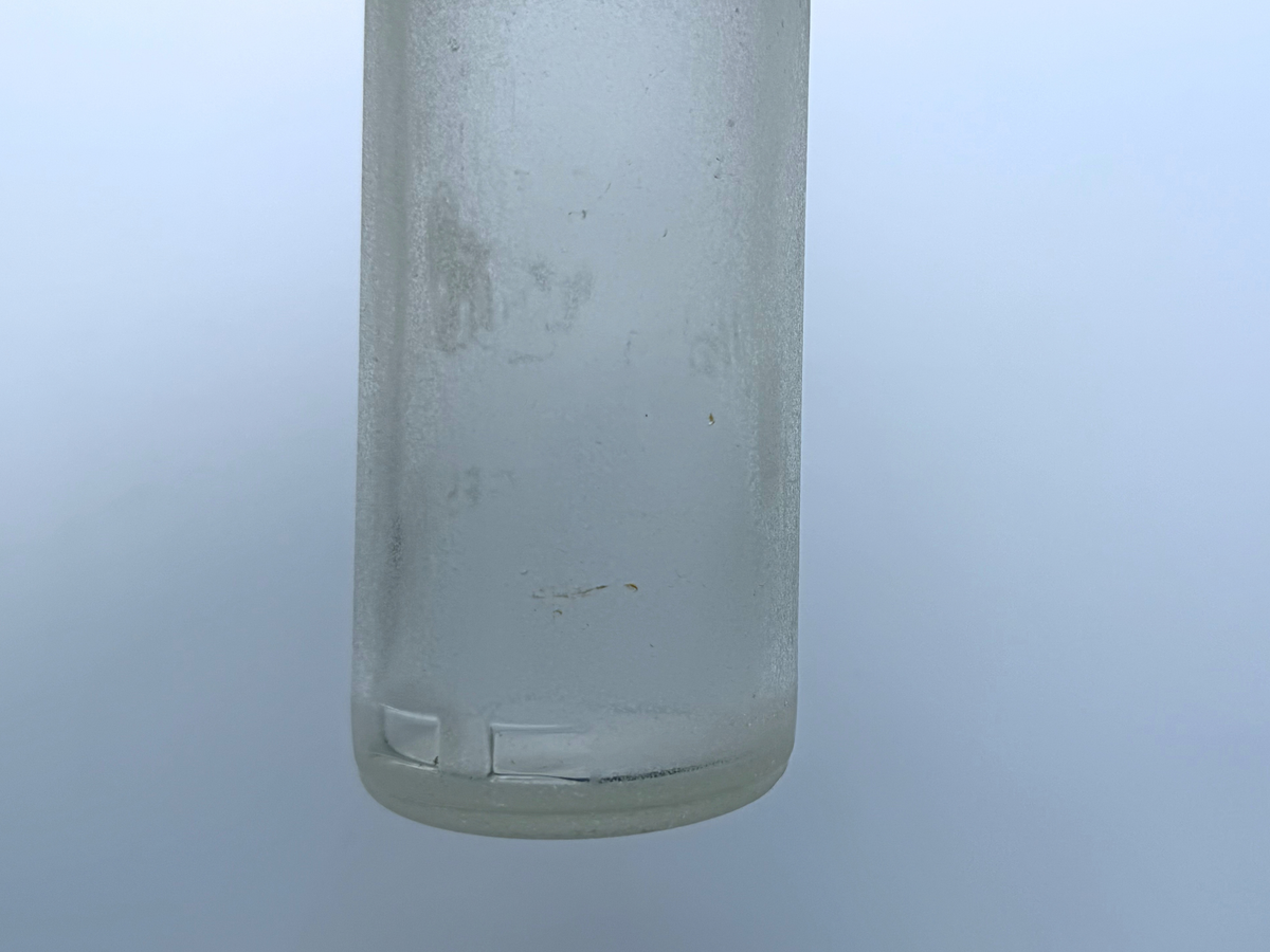 Frosted base edge of a sea-worn Hollywood soda bottle showing heavy ocean patina