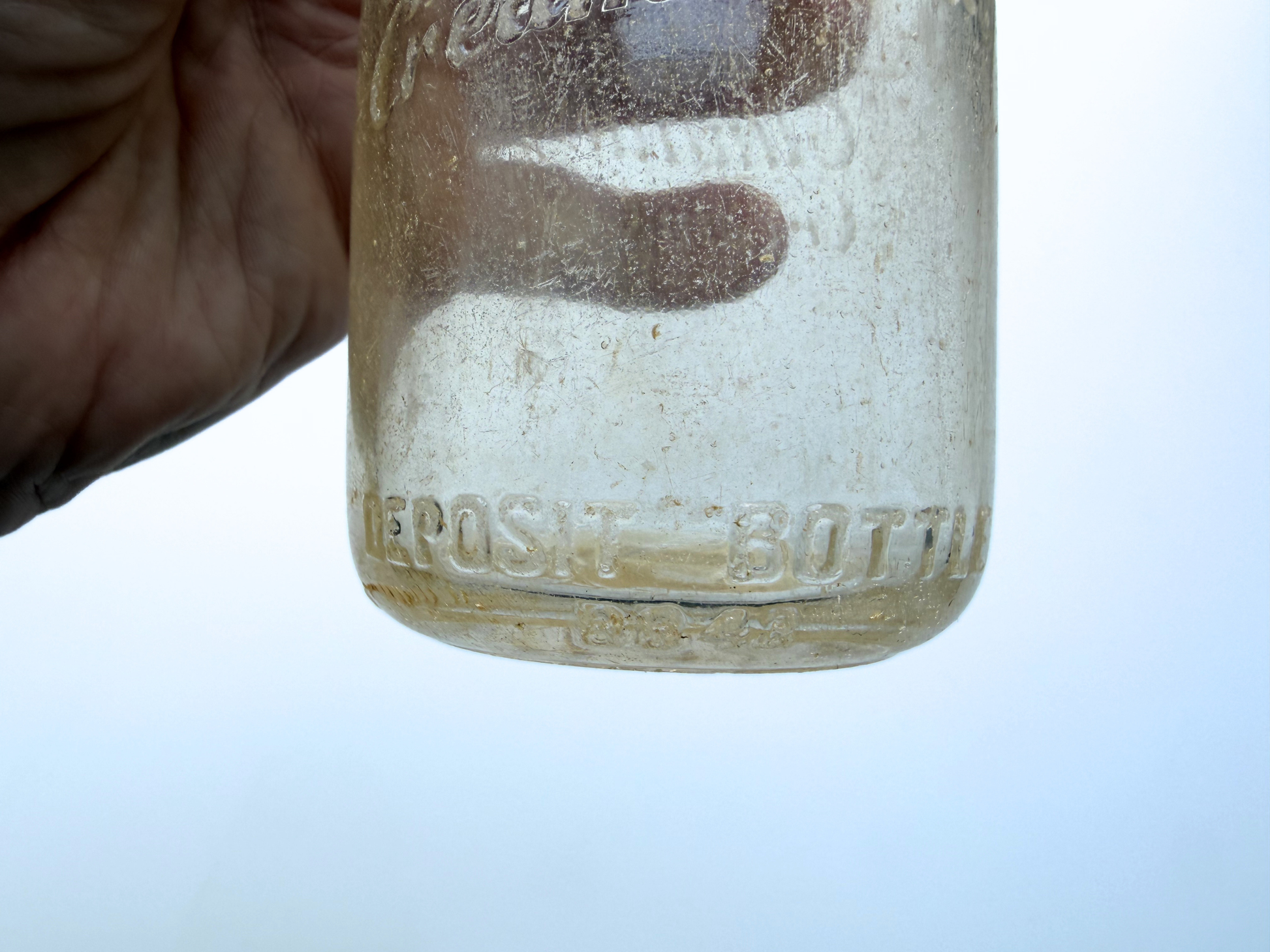 Close-up of back embossing reading Elmhurst Cream Co Inc Deposit Bottle on sea glass patina