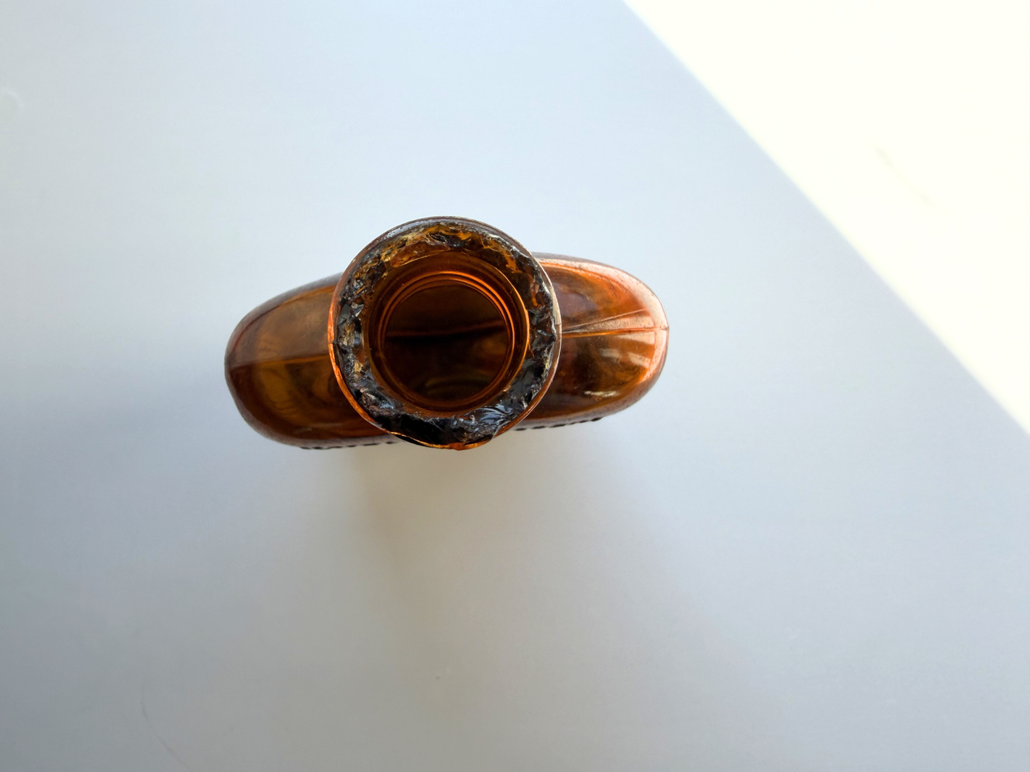 Angled top view of a sea-worn amber glass flask showing the neck and mouth