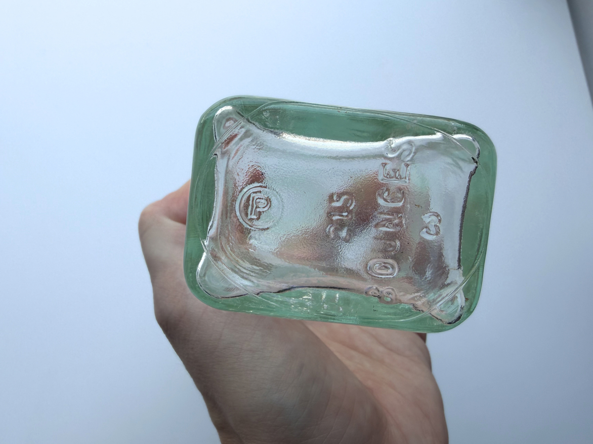 Base of the Polymol bottle held up to show the 8 ounce capacity mark and the P logo of Pierce Glass Co