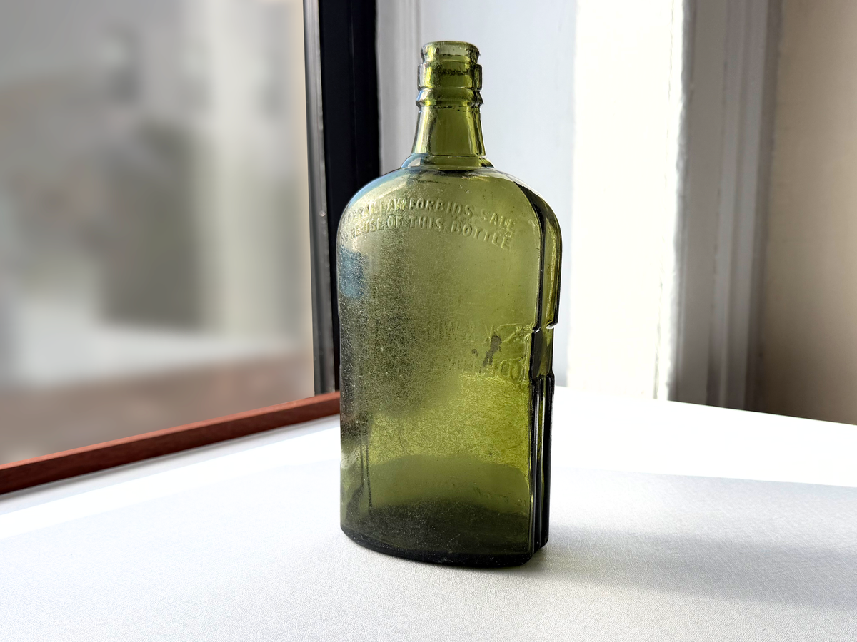 Black and White Deluxe Scotch bottle close-up showing embossing detail on green glass, Federal Law era antique barware