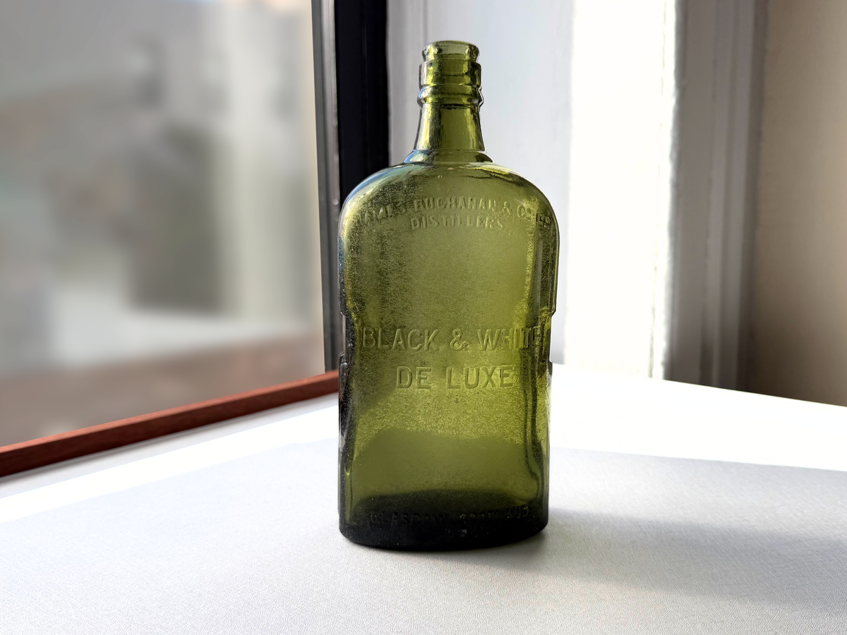 Black and White Deluxe Scotch bottle by James Buchanan and Co Glasgow Scotland, green glass with Federal Law embossing, recovered from NYC shoreline