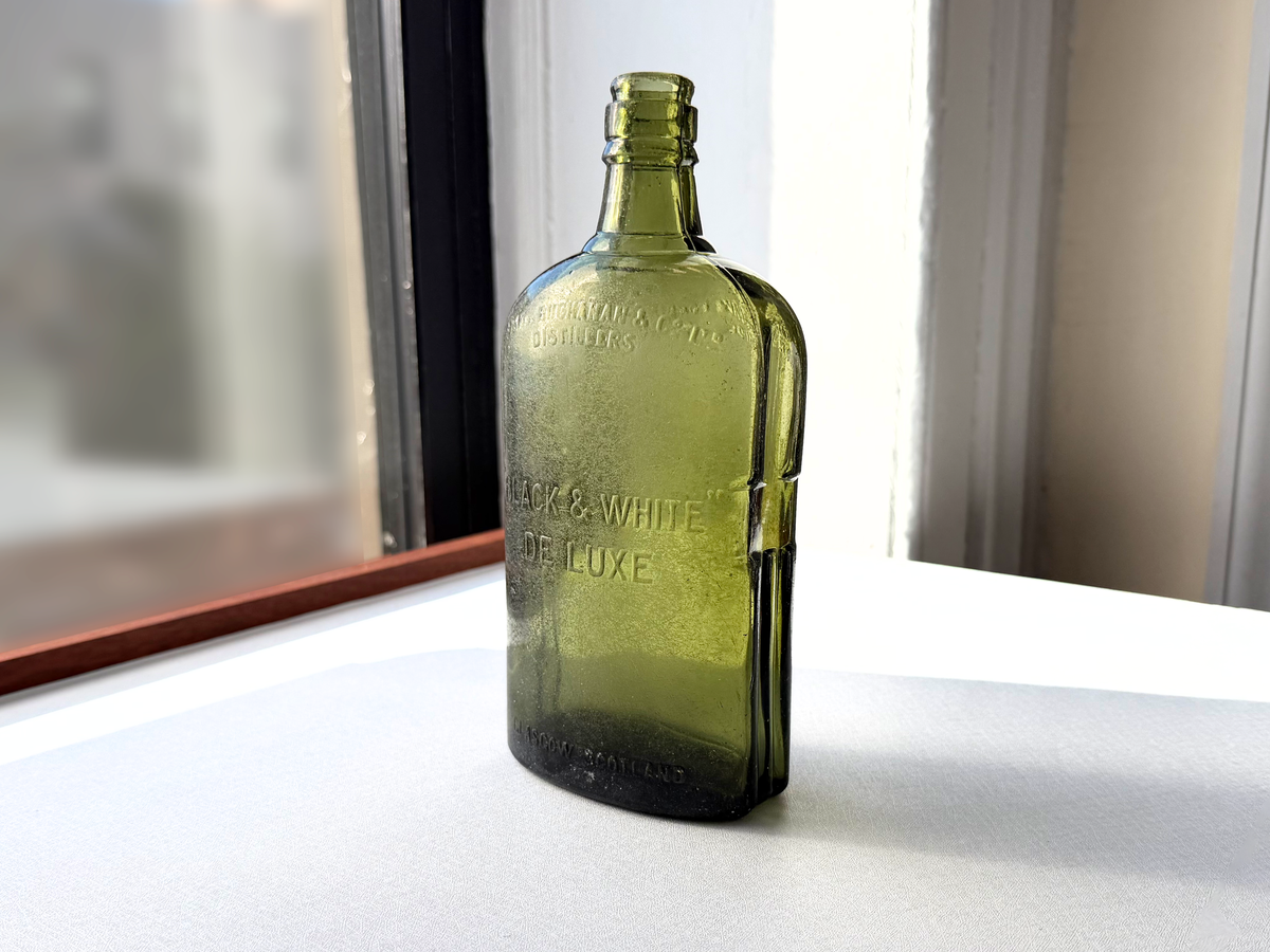 Antique Black and White Deluxe Scotch bottle detail shot, vintage green glass with seaworn patina from NYC shoreline