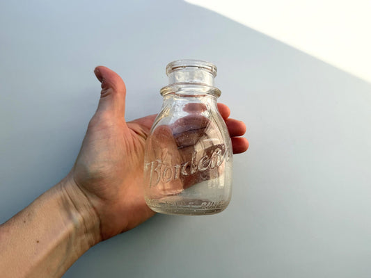 Borden's half-pint bottle held in hand for scale, compact 4.75 inch clear glass dairy form