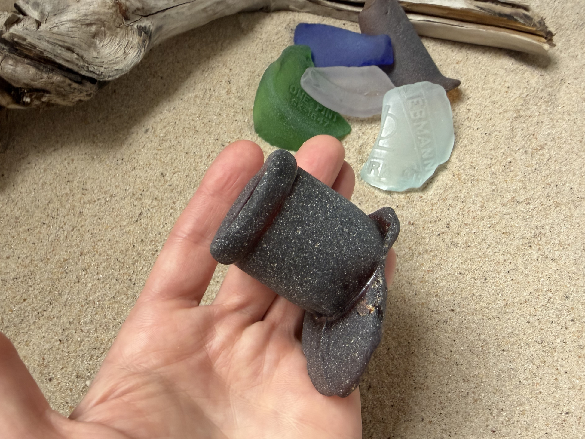 Hand holding rare dark charcoal sea glass stopper piece to show scale, large 2-3 inch authentic NYC beach find