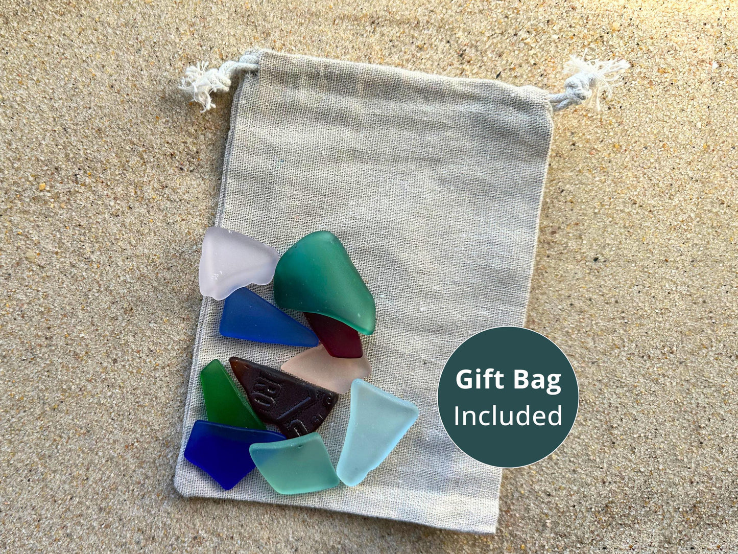 Linen gift bag on beach sand filled with large antique glass pieces in cool tones like seafoam, cobalt, and lavender. All glass is machine tumbled from repurposed vintage sources. Gift bag included with this listing—ready for gifting or creative proj
