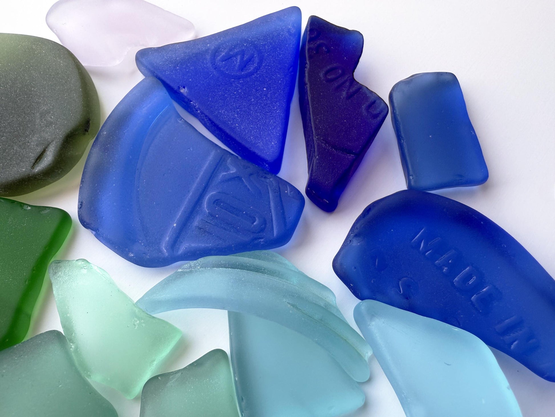 Large blue and purple sea glass with embossed letters and soft edges. Machine tumbled from vintage glass rescued from New York City. Includes cobalt and navy tones perfect for nautical or coastal-themed art. Rich patina and smooth matte finish.