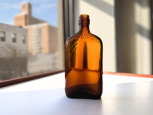 Vintage 1949 amber glass spirits flask 8.25 inches tall with Federal Law embossing around shoulder - clean mid-century collector piece hand-recovered from NYC