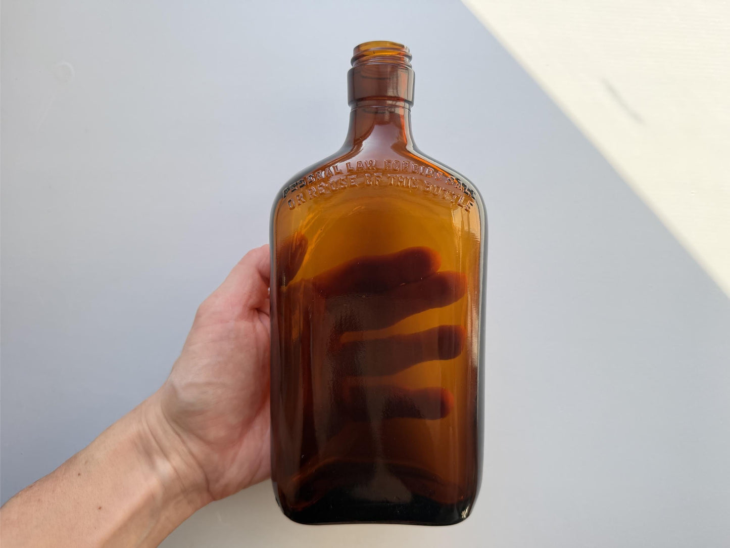 Vintage 1949 amber glass spirits flask 8.25 inches tall with Federal Law embossing around shoulder - clean mid-century collector piece hand-recovered from NYC