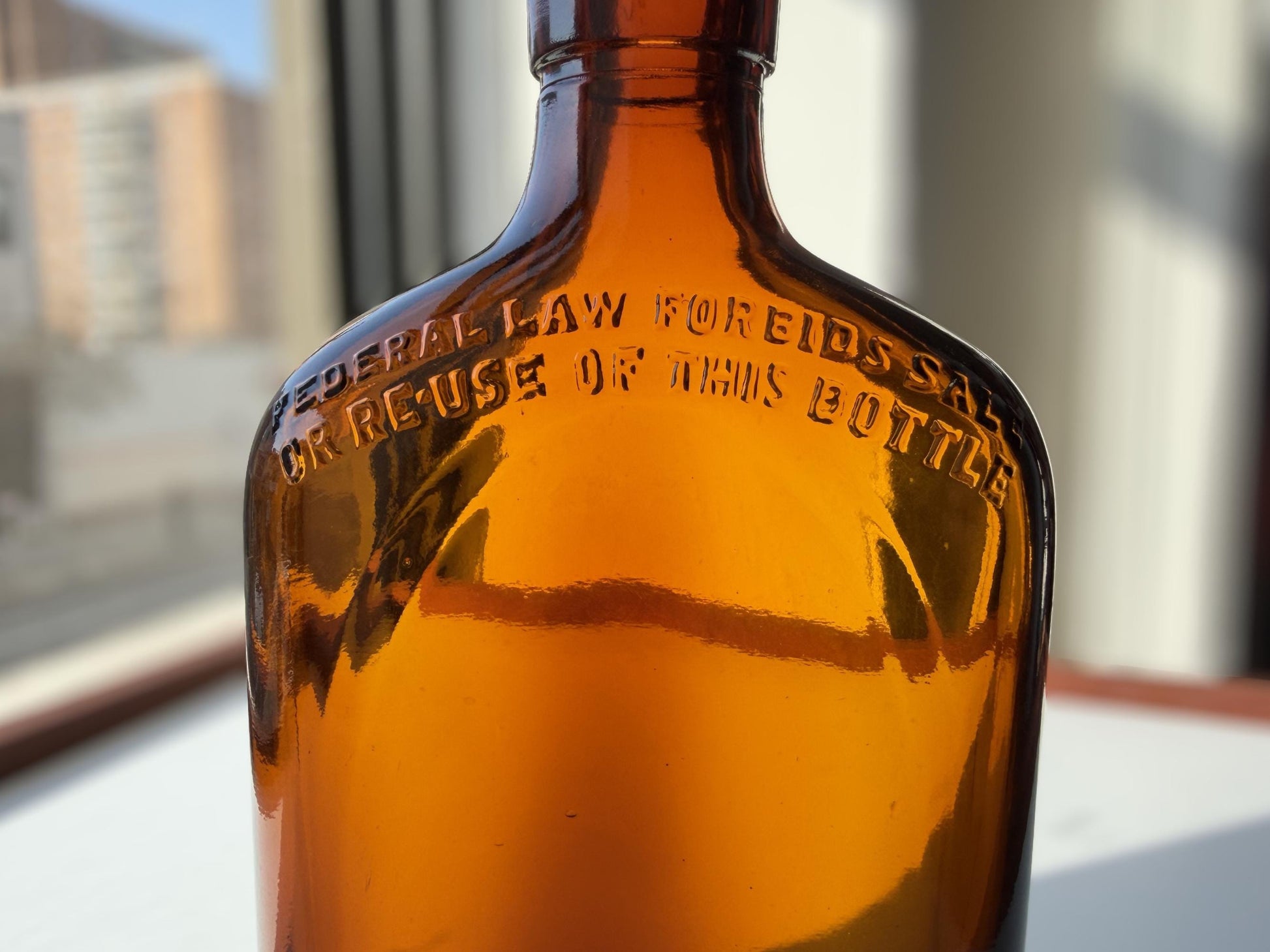 Vintage 1949 amber glass spirits flask 8.25 inches tall with Federal Law embossing around shoulder - clean mid-century collector piece hand-recovered from NYC