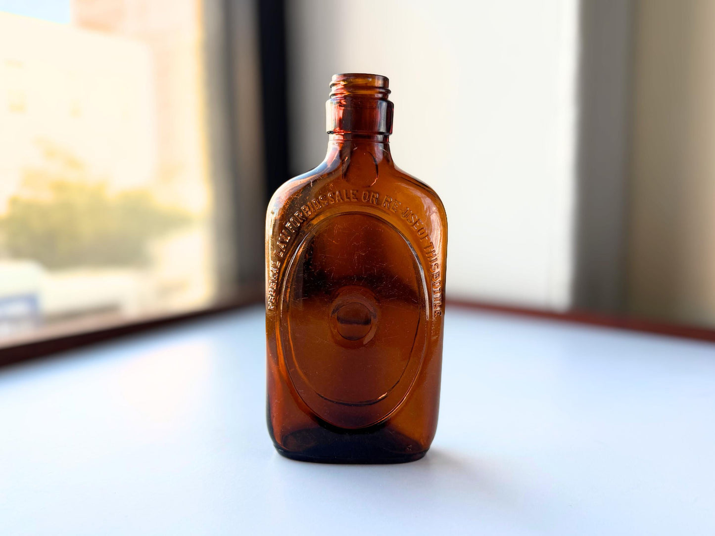 Vintage 1950s amber glass liquor flask 6.75 inches tall with oval embossing and Federal Law prohibition warning. Art Deco oval design, rescued from NYC historic landfills – Brooklyn Sea Glass