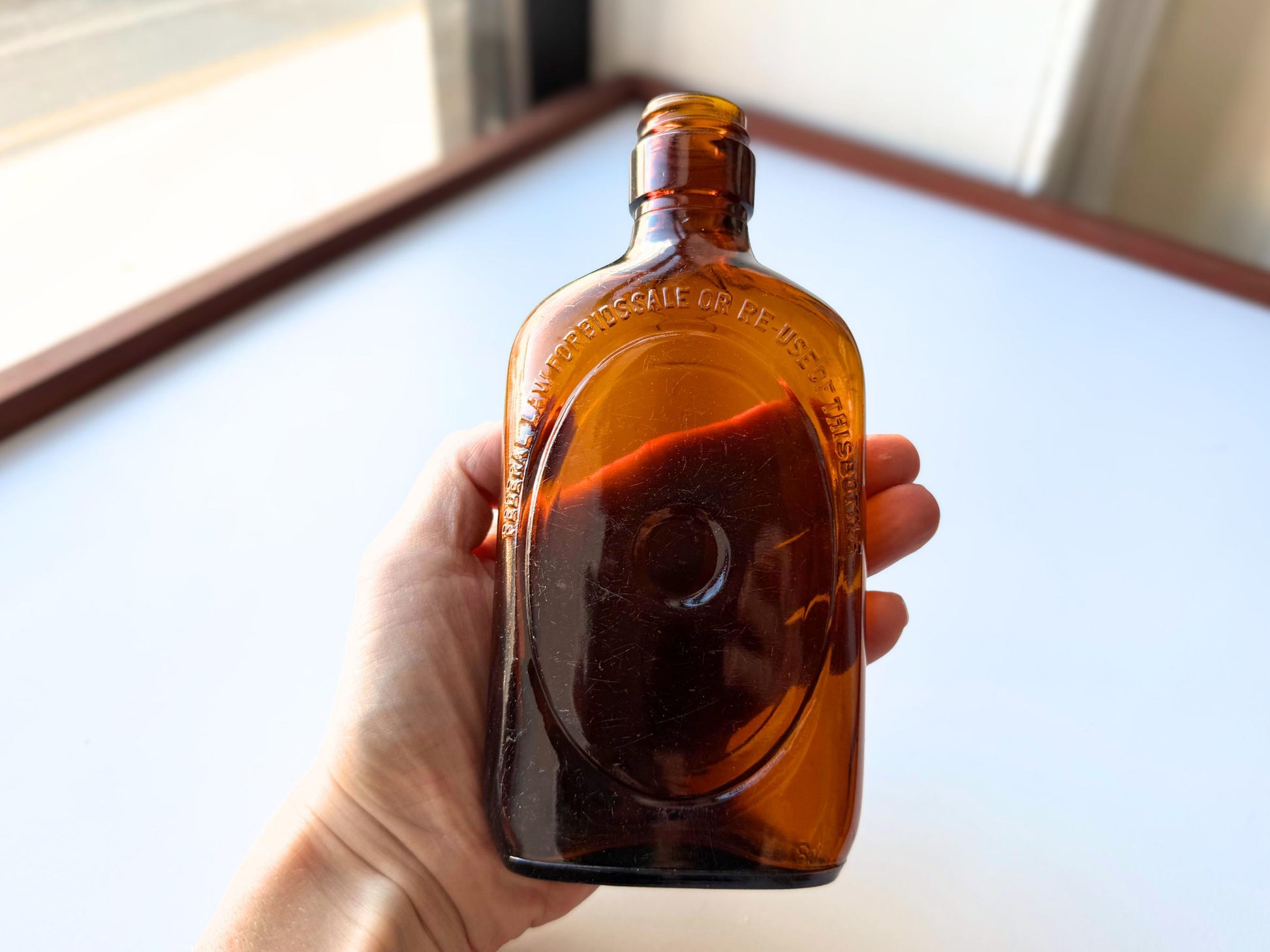 Vintage 1950s amber glass liquor flask 6.75 inches tall with oval embossing and Federal Law prohibition warning. Art Deco oval design, rescued from NYC historic landfills – Brooklyn Sea Glass