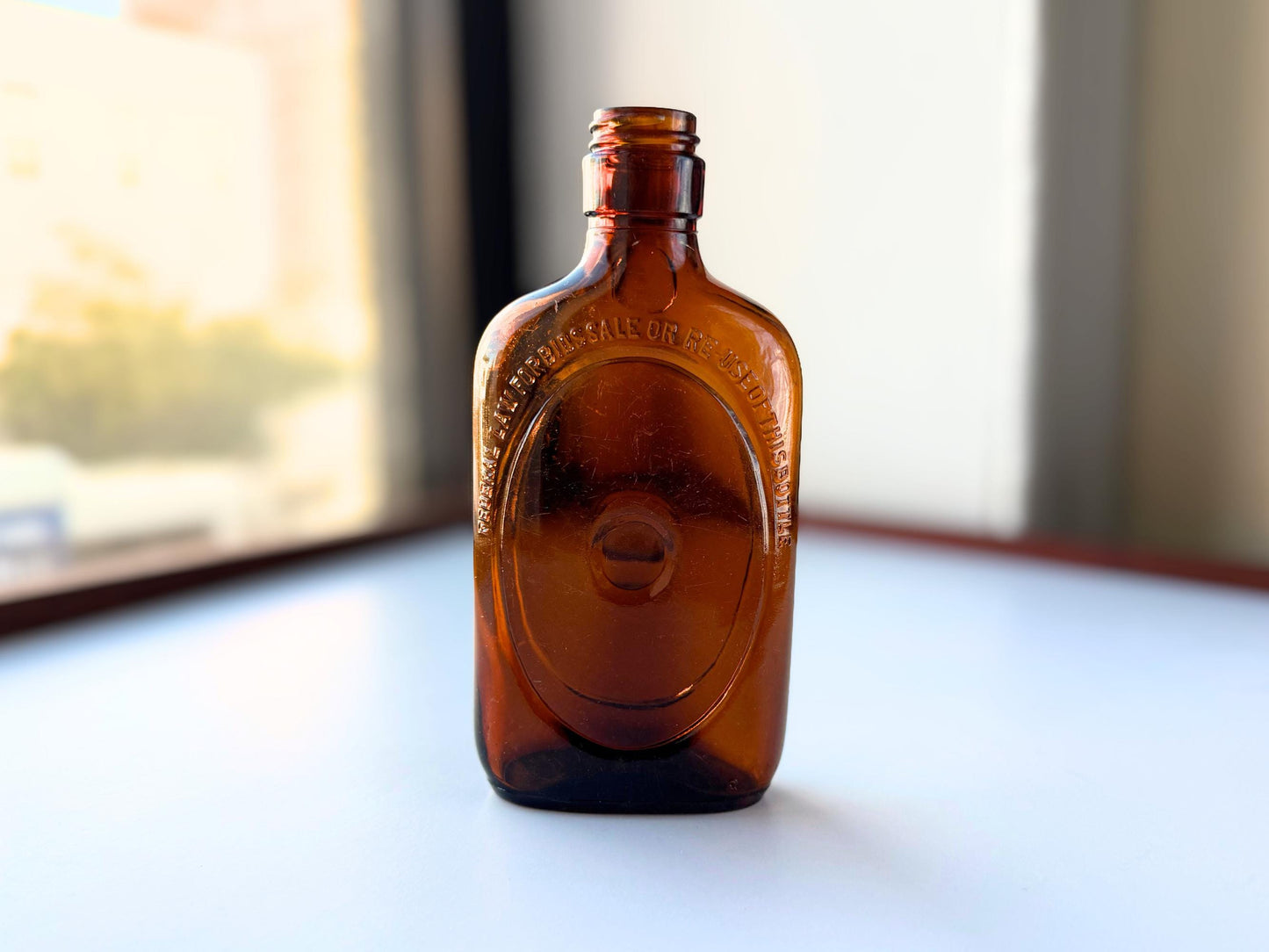 Vintage 1950s amber glass liquor flask 6.75 inches tall with oval embossing and Federal Law prohibition warning. Art Deco oval design, rescued from NYC historic landfills – Brooklyn Sea Glass
