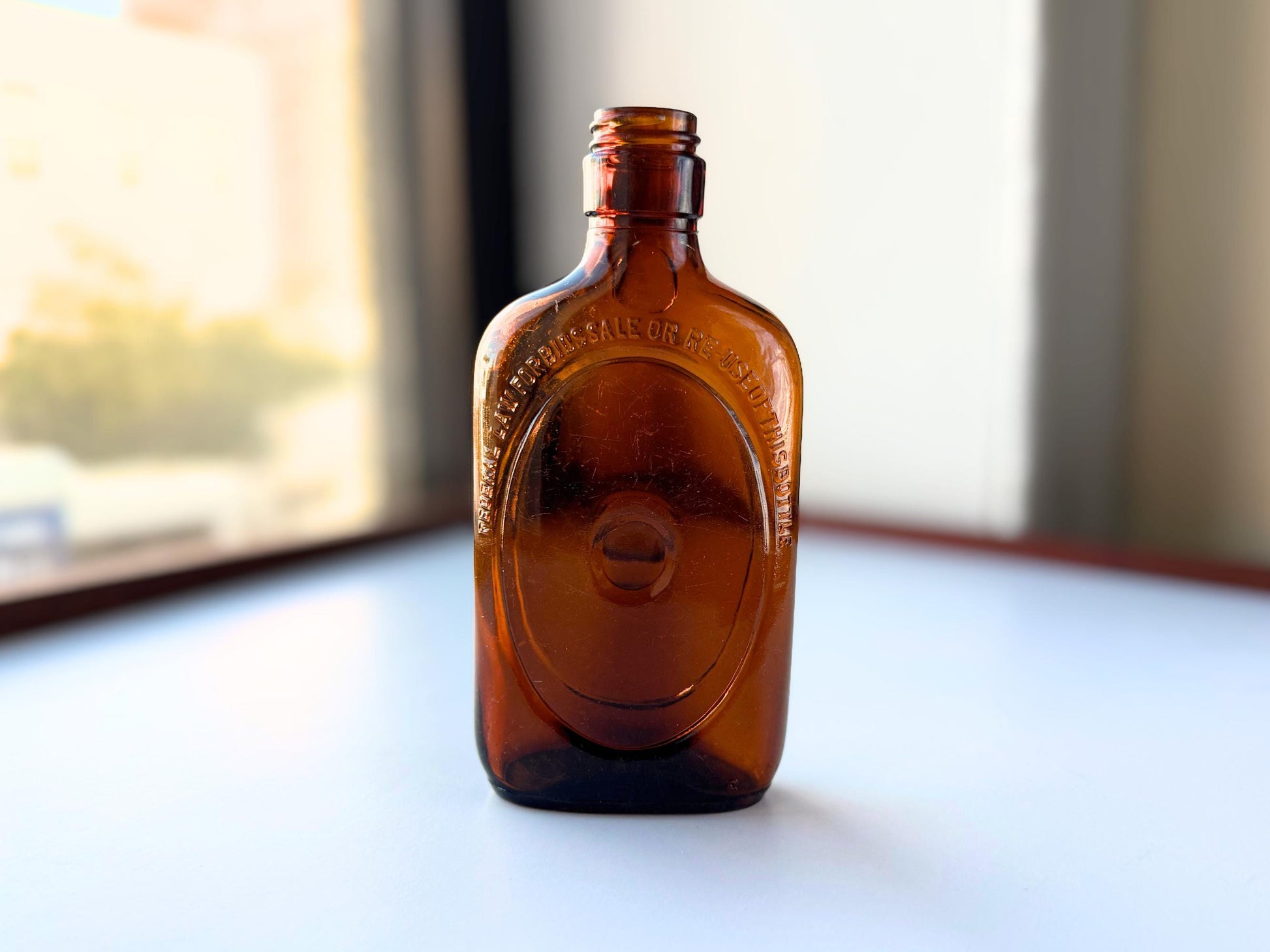 Vintage 1950s amber glass liquor flask 6.75 inches tall with oval embossing and Federal Law prohibition warning. Art Deco oval design, rescued from NYC historic landfills – Brooklyn Sea Glass