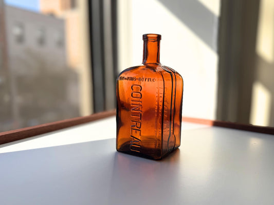 Vintage 1951 large amber Cointreau bottle with 51 production marking. Perfect for spirits collectors, bar displays, and vintage liqueur enthusiasts.