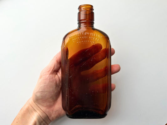 Vintage 1952 mid-century amber glass flask 7.5 inches tall by 3.4 inches wide, rescued from NYC beaches. Ribbed design with embossed Federal Law Forbids Sale Or Reuse Of This Bottle text – Brooklyn Sea Glass