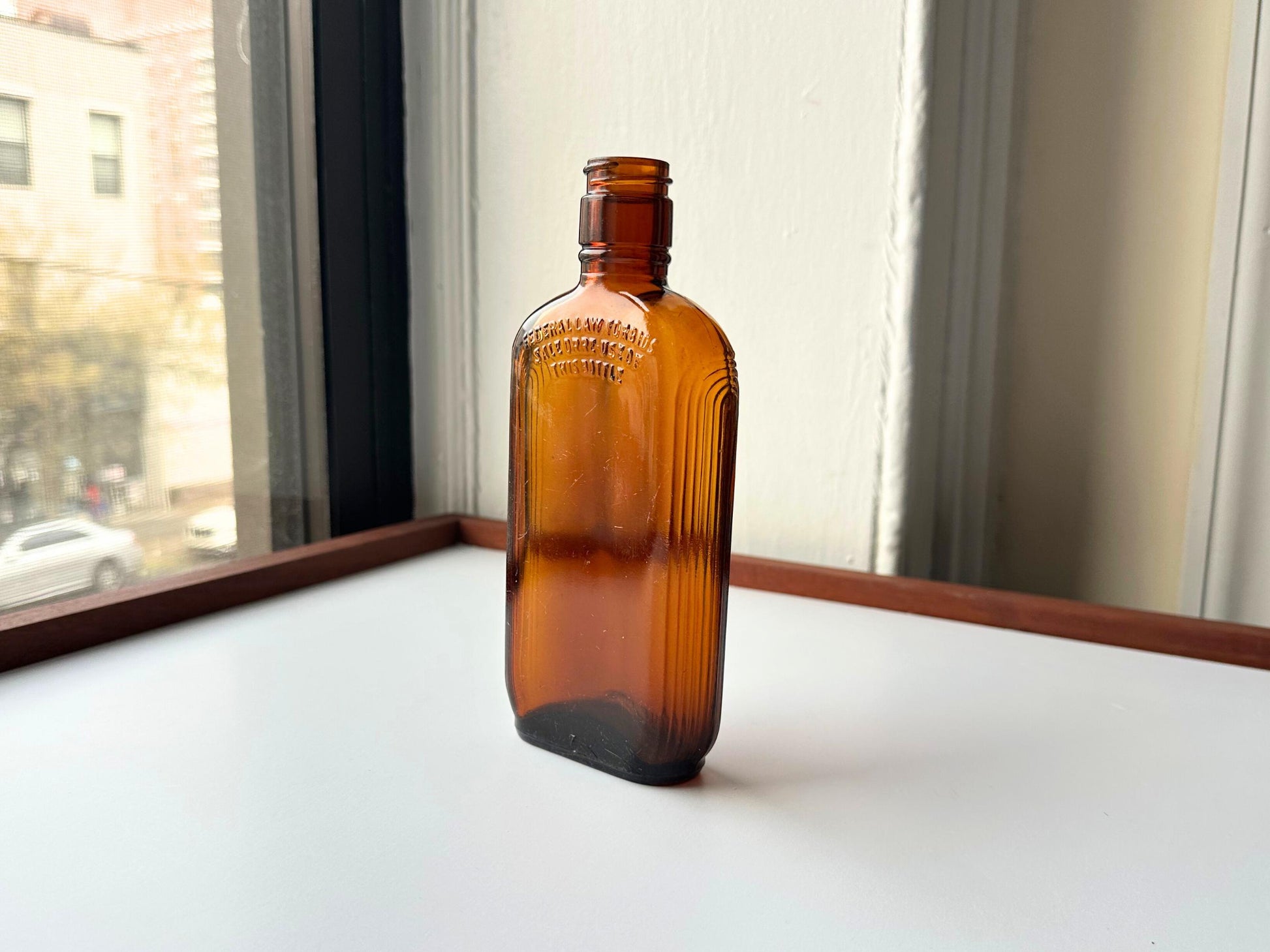 Vintage 1952 mid-century amber glass flask 7.5 inches tall by 3.4 inches wide, rescued from NYC beaches. Ribbed design with embossed Federal Law Forbids Sale Or Reuse Of This Bottle text – Brooklyn Sea Glass
