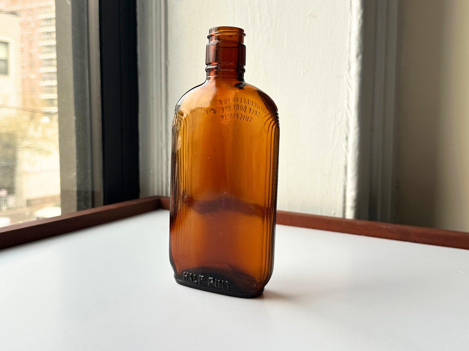 Vintage 1952 mid-century amber glass flask 7.5 inches tall by 3.4 inches wide, rescued from NYC beaches. Ribbed design with embossed Federal Law Forbids Sale Or Reuse Of This Bottle text – Brooklyn Sea Glass