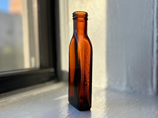 Amber vintage Father John's Medicine bottle with embossed lettering sitting on a windowsill – Brooklyn Sea Glass