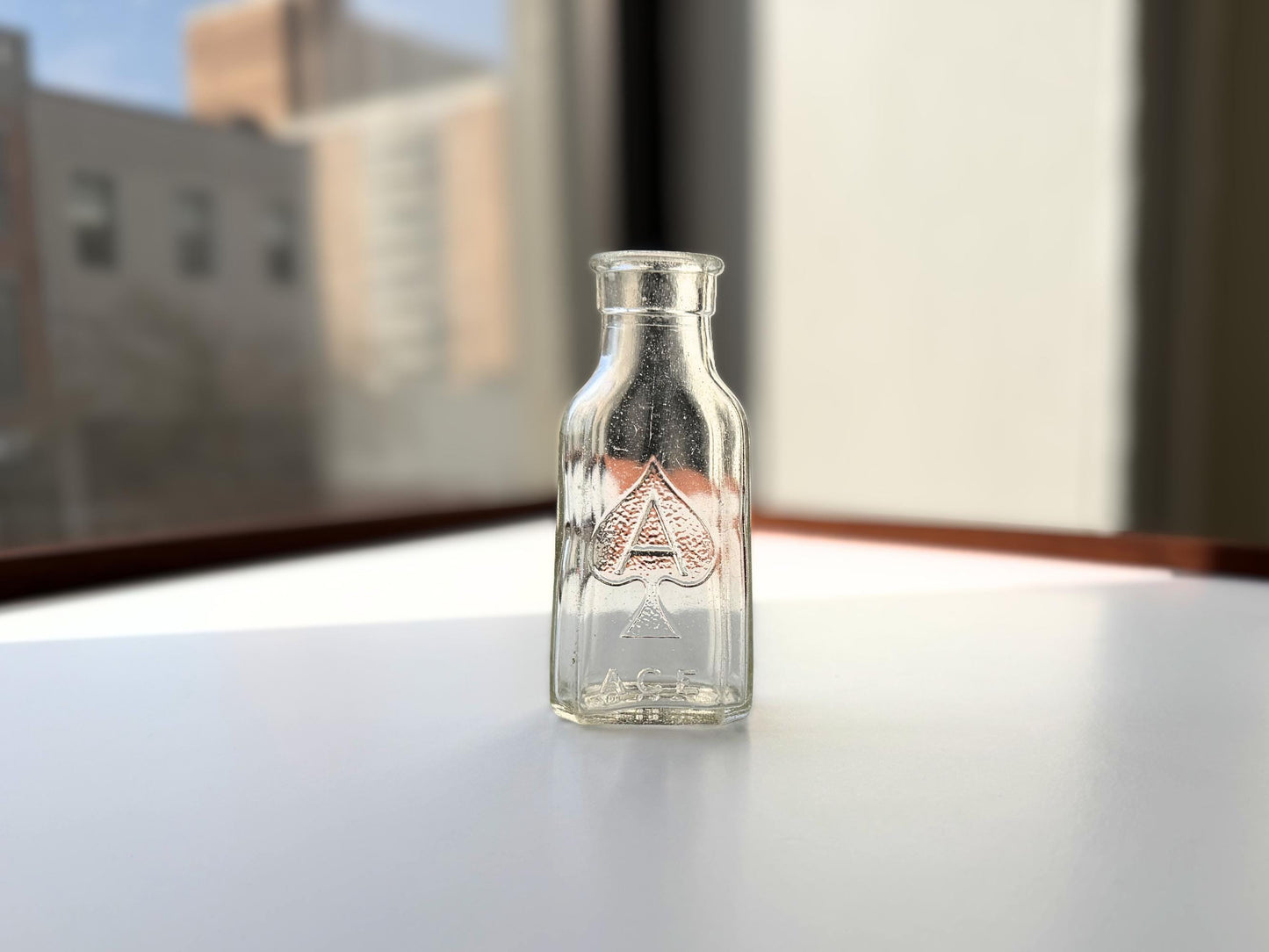 Vintage clear glass Ace shoe polish bottle 4.25 inches tall with bold ace-of-spades embossed logo - mid-century American collector piece hand-recovered from NYC